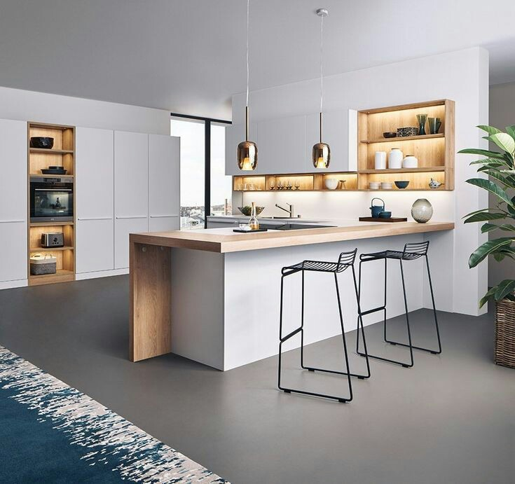 Perpaduan kayu dan warna putih yang sleek memang cocok untuk model dapur yang mengedepankan kesan minimalis. Meja kayu dan lemari terlihat manis dipadukan dengan kursi sederhana berwarna hitam