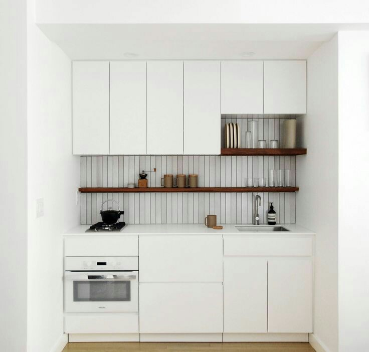 Dapur kecil ini hanya memanfaatkan satu bagian dinding namun terlihat sangat menarik. Warna putih dari kitchen set menyatu sempurna dengan cat dinding. Namun adanya rak dan corak garis dibagian tengah menjadikan dapur tidak monoton