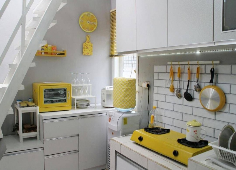 Manfaatkan ruang yang ada pada bagian bawah tangga sebagai dapur anda. Dan untuk menghindari kesan ramai, pilih warna netral seperti putih dengan sedikit sentuhan warna lain yang lebih mencolok seperti kuning untuk menghidupkan area dapur