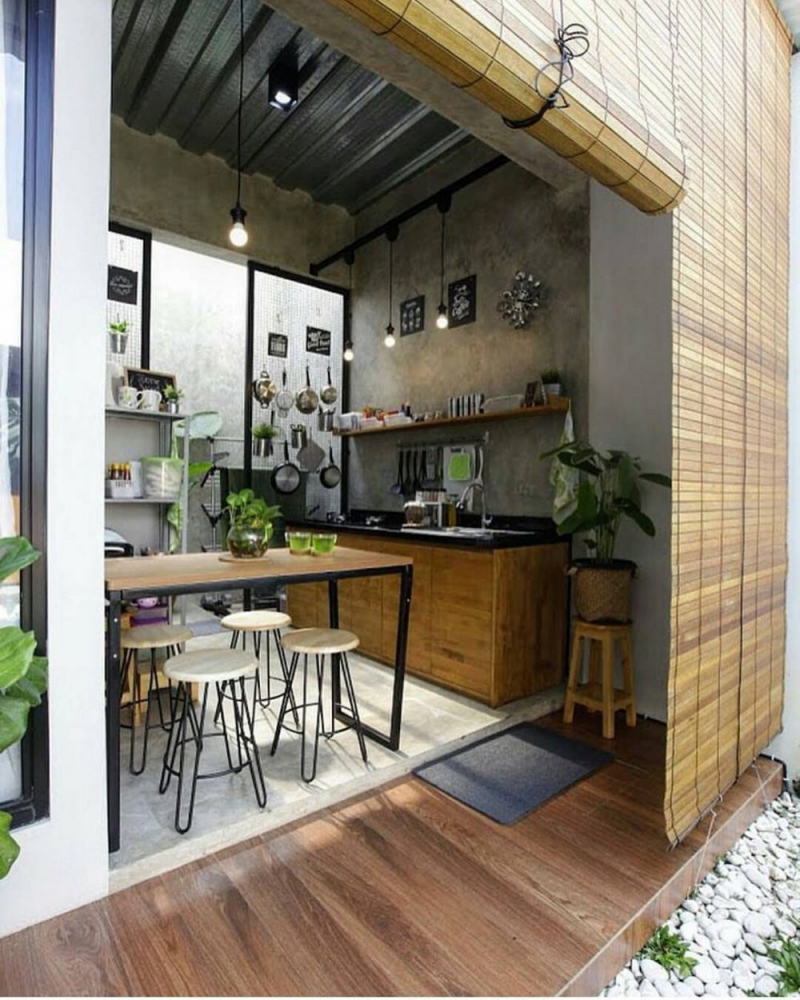 Tema industrial terlihat dari finishing dinding yang tampak seperti semen. Untuk furnitur, amannya memilih yang berbahan kayu dengan countertop hitam. Tidak lupa lampu gantung yang simpel