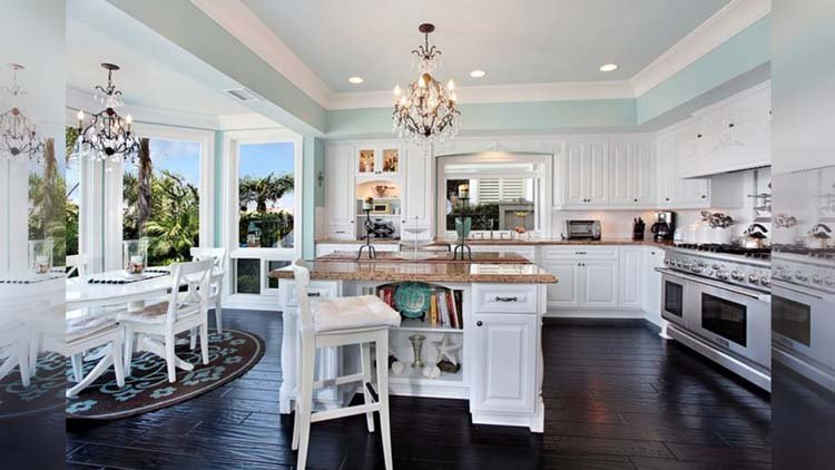 Kitchen set yang mengikuti lekukan dinding ini mempunyai nilai estetik tinggi saat dipadukan dengan island dapur yang memiliki countertop dari batu marmer berwarna cokelat. Penempatan kaca pada sisi kitchen set juga semakin membuat dapur menarik