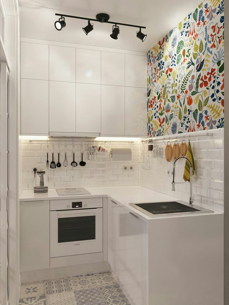 Berikan salah satu sisi dinding dapur wallpaper dengan corak bunga warna-warni yang cantik seperti contoh di bawah ini. Sebagai pemanis di area dapur yang didominasi warna putih, anda juga bisa menambahkan lampu berangka besi hitam