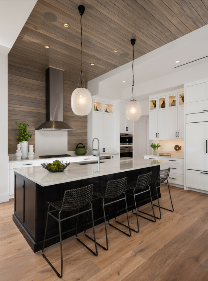 Warna netral memang sangat aman untuk dapur, namun untuk memberikan nuansa mewah, anda bisa memberikan sentuhan material kayu dengan warna gelap dan dinding kayu yang tersambung hingga ke langit-langit