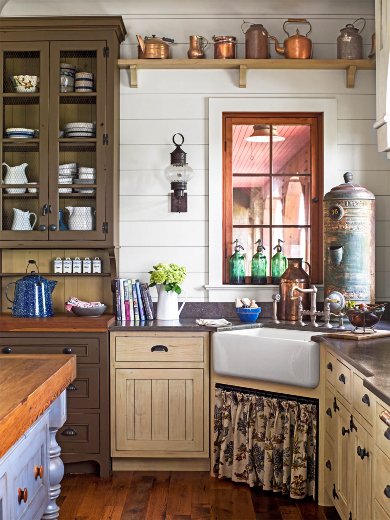 Untuk anda yang suka dengan tema jadul pada ruang dapur, pilih dekorasi dapur yang sesuai seperti contohnya beberapa teko vintage yang terbuat dari perunggu untuk dipajang di rak kayu atas. Tidak lupa lampu tempel dari logam berwarna gelap
