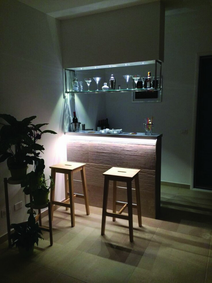 Tidak perlu banyak furnitur untuk membuat minibar di rumah. Dengan meja slim panjang dari material batu dan rak botol di bagian atas, anda sudah bisa memiliki minibar. Tidak lupa pengaturan pencahayaan pada bawah meja