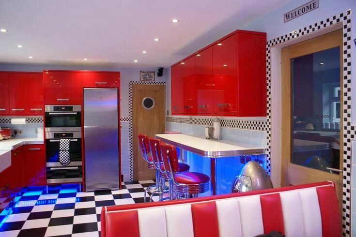 Desain dapur anda dengan kitchen set berwarna merah dengan finishing glossy dan kursi bertema retro yang keren. Tidak lupa tambahkan lampu led dengan warna biru sebagai pelengkap tema retro