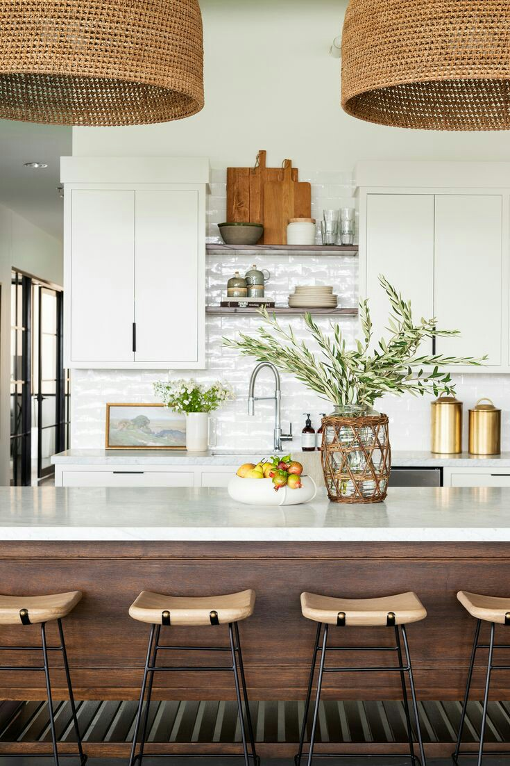 Perpaduan putih dan kayu membuat dapur ini hangat dan terkesan nyaman. Pemilihan kursi berbahan kayu dengan desain simpel dan lampu rotan gantung semakin menyatukan penampilan dapur