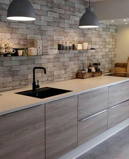 Pemilihan kitchen set dengan desain sederhana memang penting untuk dapur bertema minimalis modern. Material kayu dengan aksen granit putih pada countertop menyatu dengan dinding batu bata berwarna abu-abu